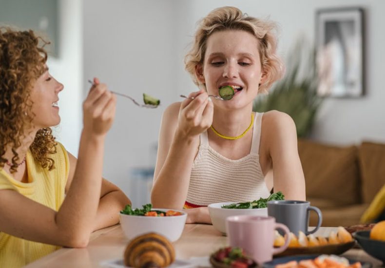 Two women enjoying a healthy meal at a cozy dining table, sharing a joyful indoor breakfast moment.