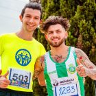 Two men posing happily with marathon bibs, outdoors on a sunny day.