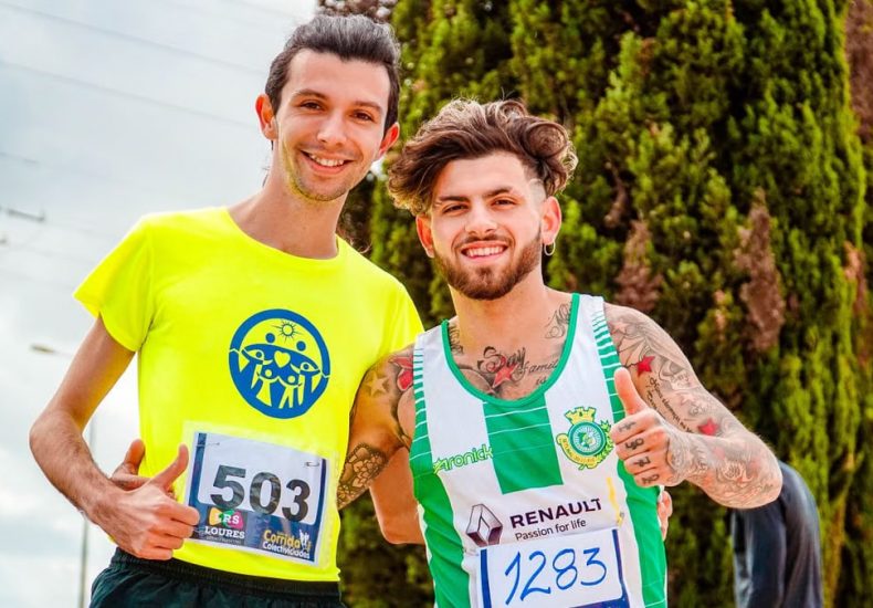 Two men posing happily with marathon bibs, outdoors on a sunny day.